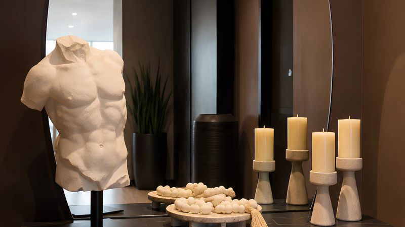 Escultura de gran formato en una sala cálida sobre consola de madera.