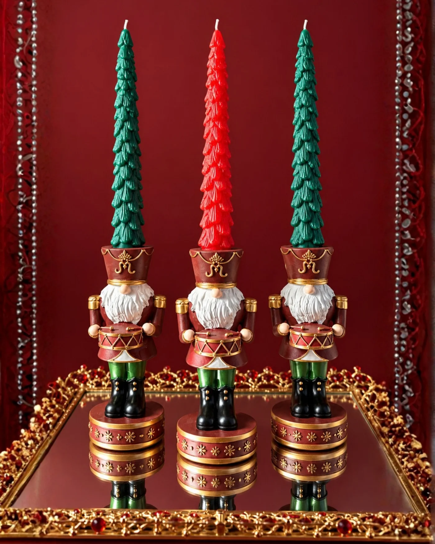 Dos soportes decorativos navideños con velas verdes de distinta altura sobre una superficie de madera oscura.