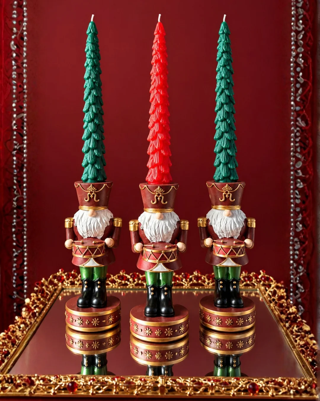 Dos soportes decorativos navideños con velas verdes de distinta altura sobre una superficie de madera oscura.