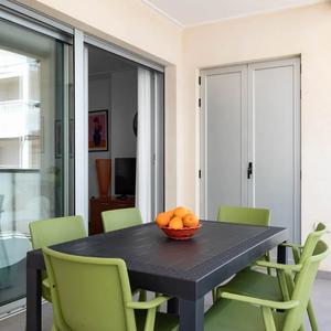 Mesa negra con seis sillas verdes y centro de mesa decorativo con naranjas en el balcón de la casa de la Playa de Miramar