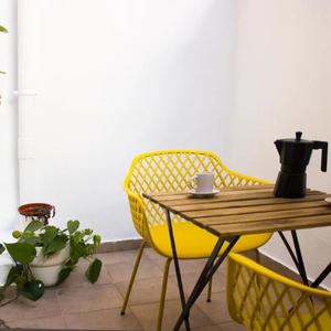 Mesa de madera con dos sillas amarillas en el patio interno del apartamento del centro de Gandia
