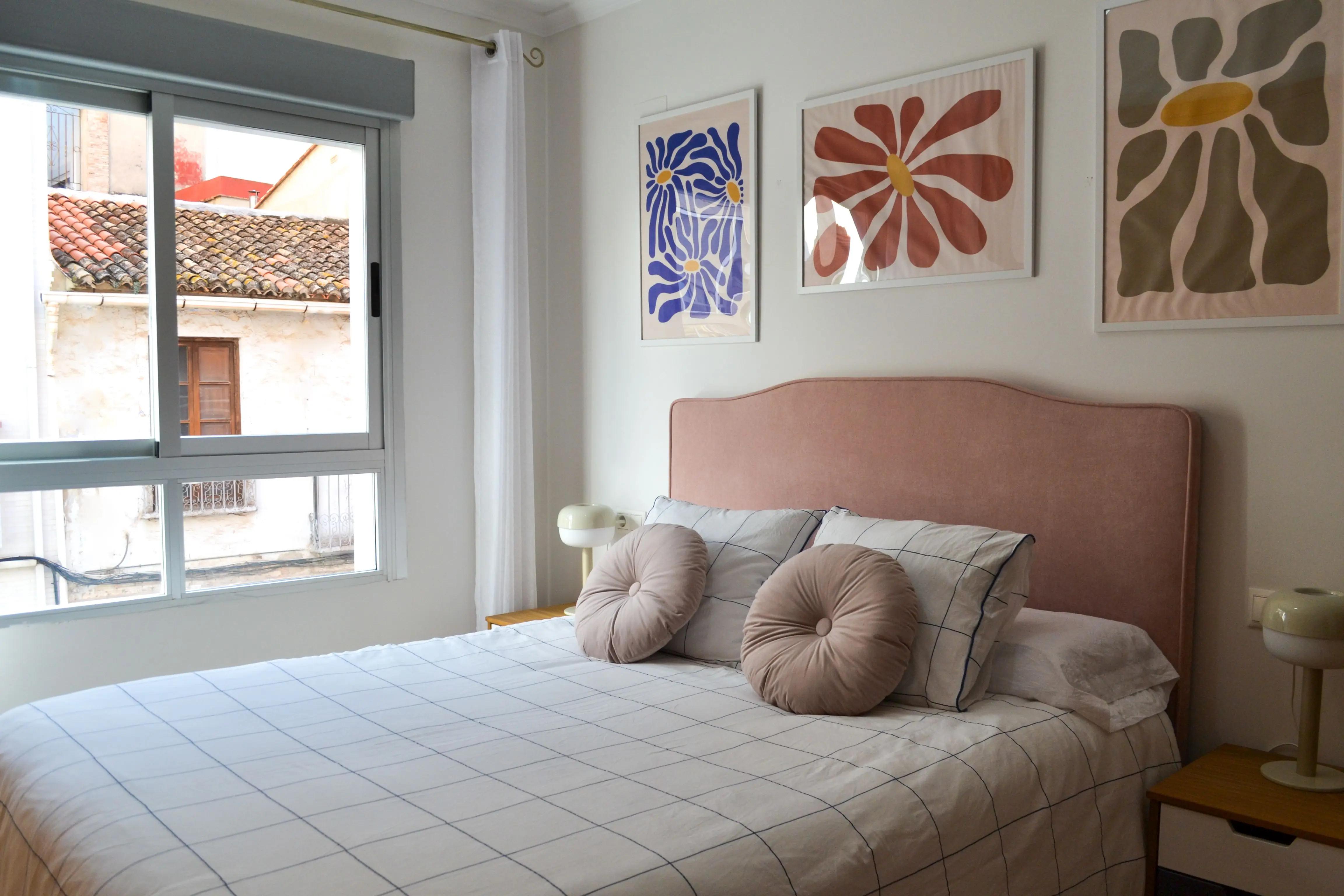Cama doble con almohadones del dormitorio principal del apartamento de Gandia