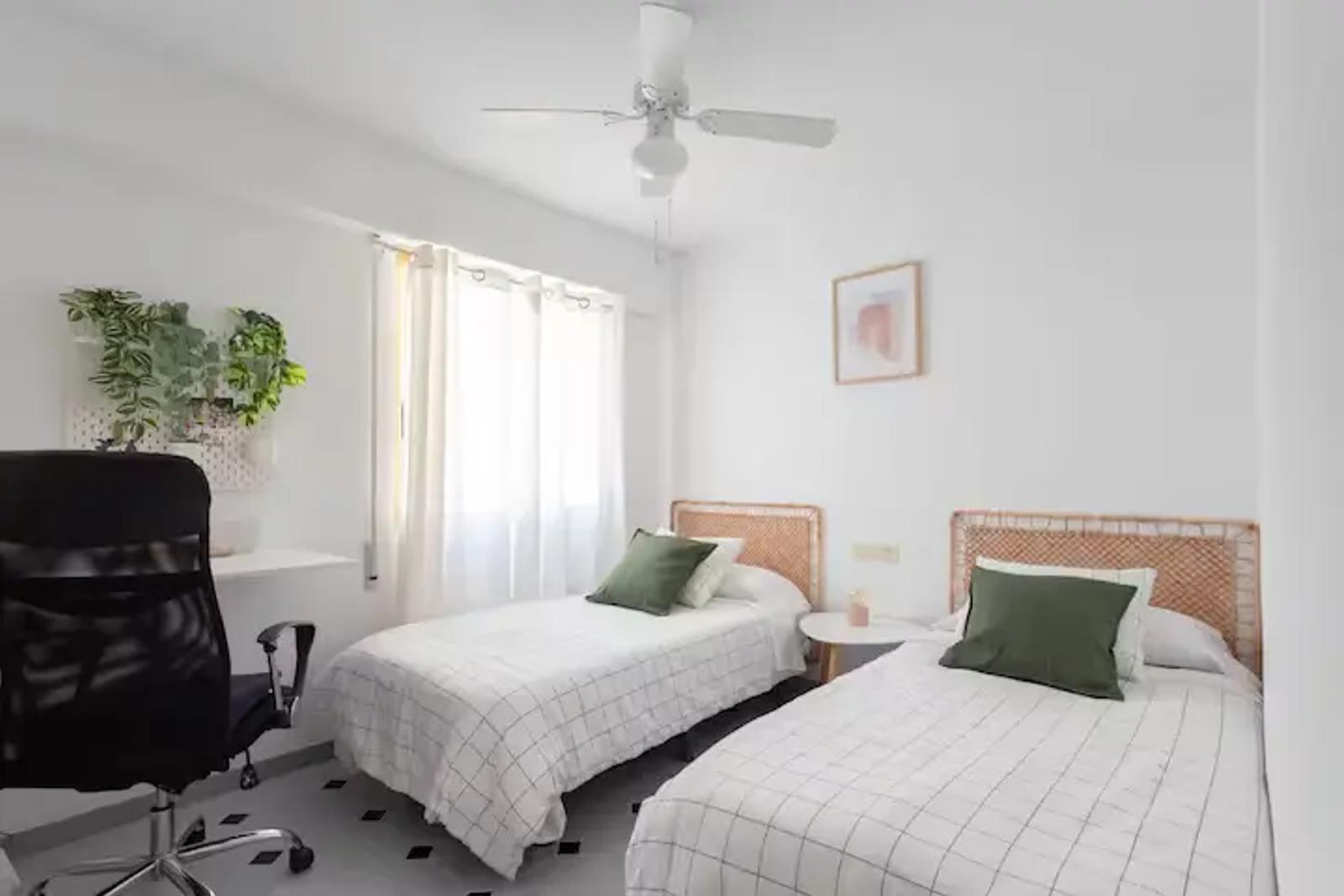Dormitorio con dos camas individuales y escritorio con silla en el apartamento de la Playa de Miramar