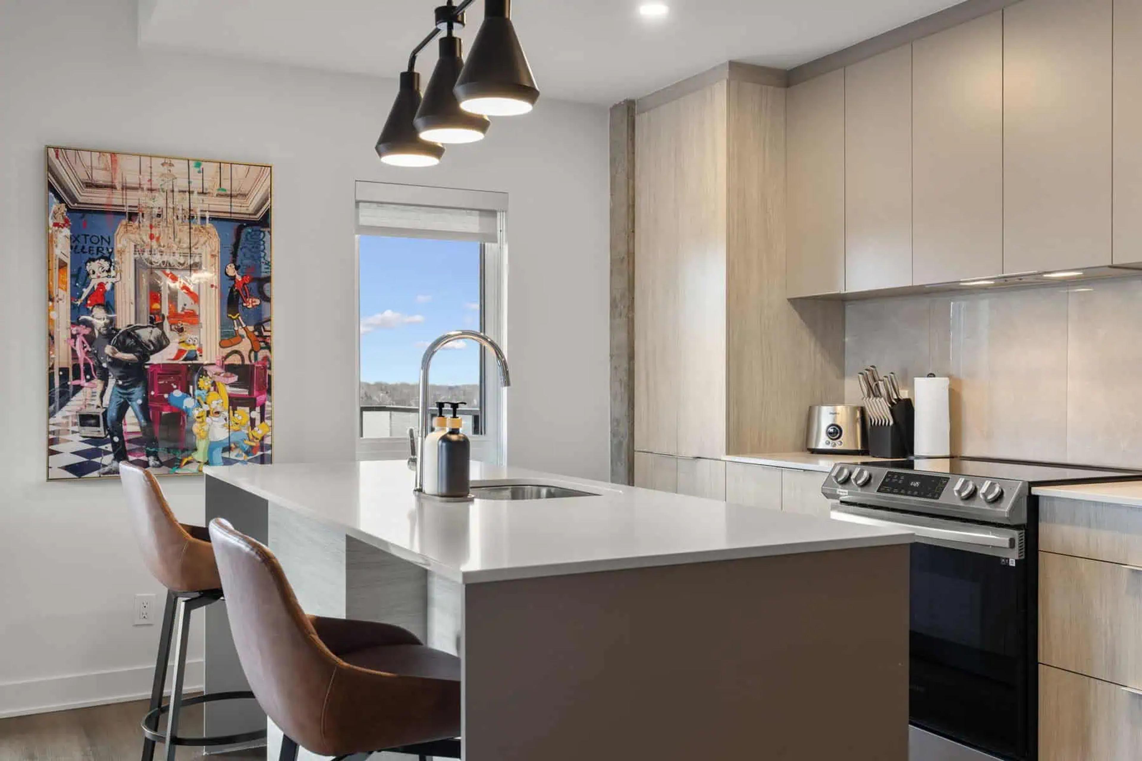 Cuisine moderne et équipée d’un logement Kondo avec îlot et tabourets