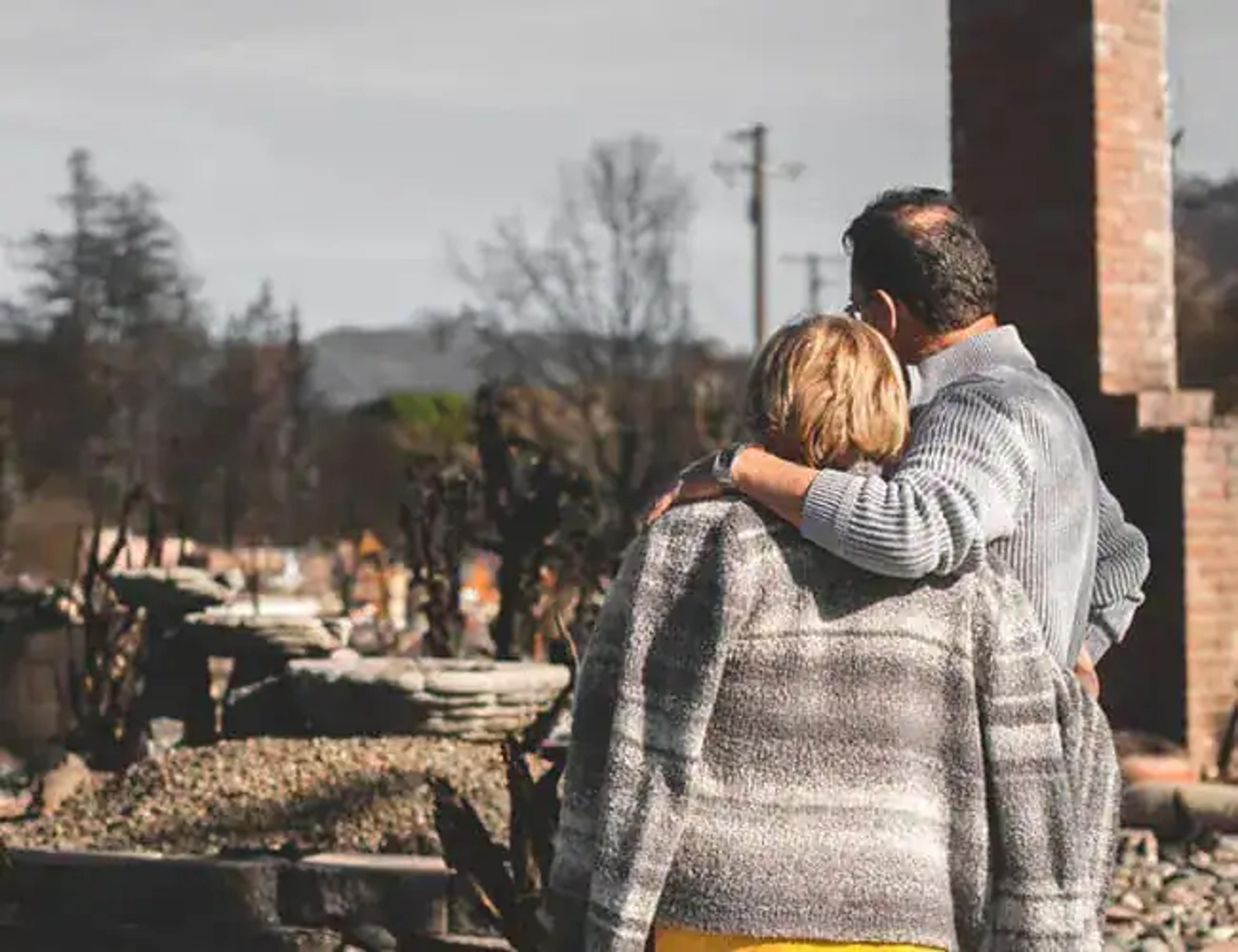 Couple enlacé devant les ruines de sa maison après un sinistre