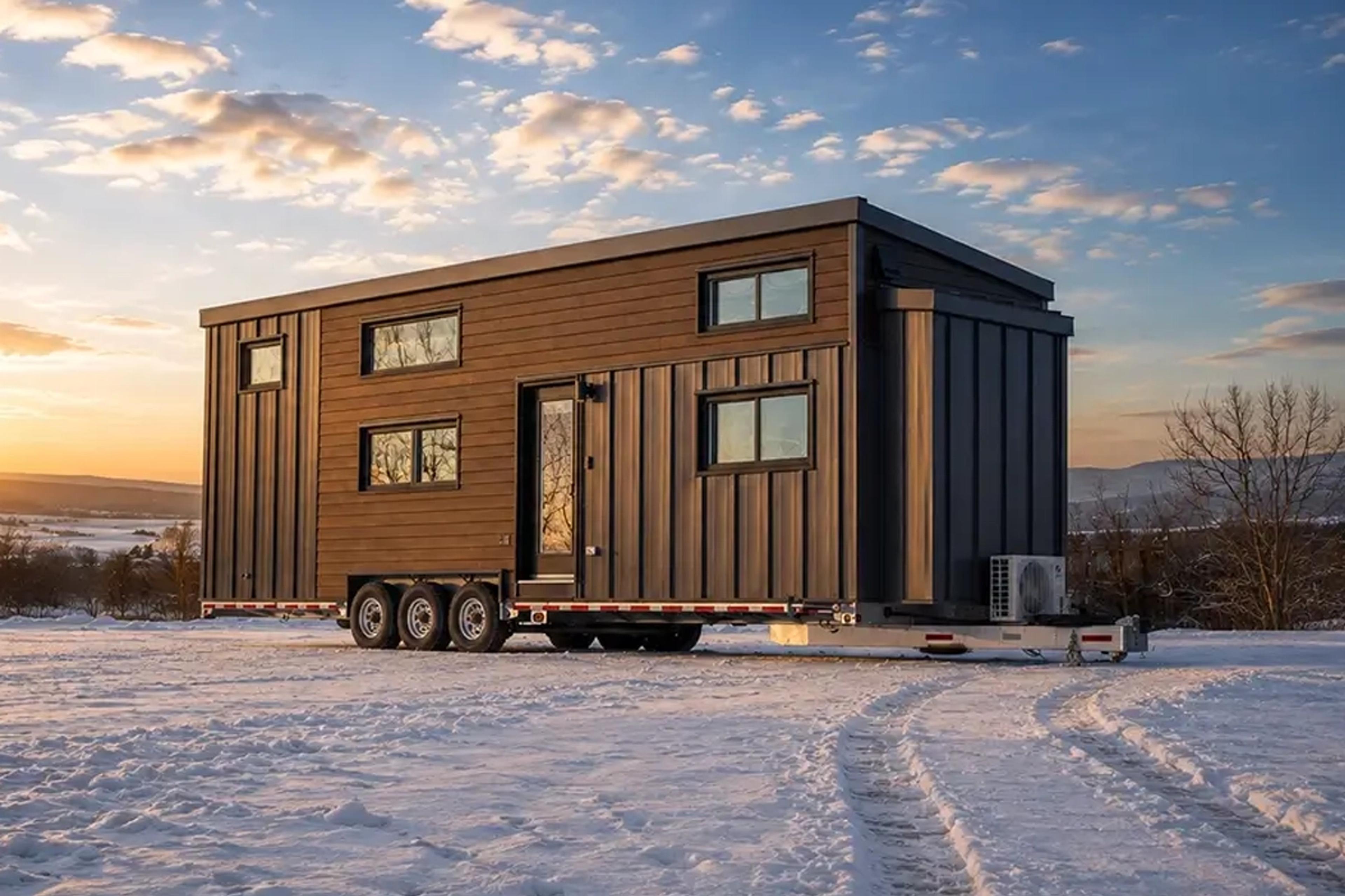 Minimaison Nomade Kondo en bois installée sur un terrain enneigé au coucher du soleil