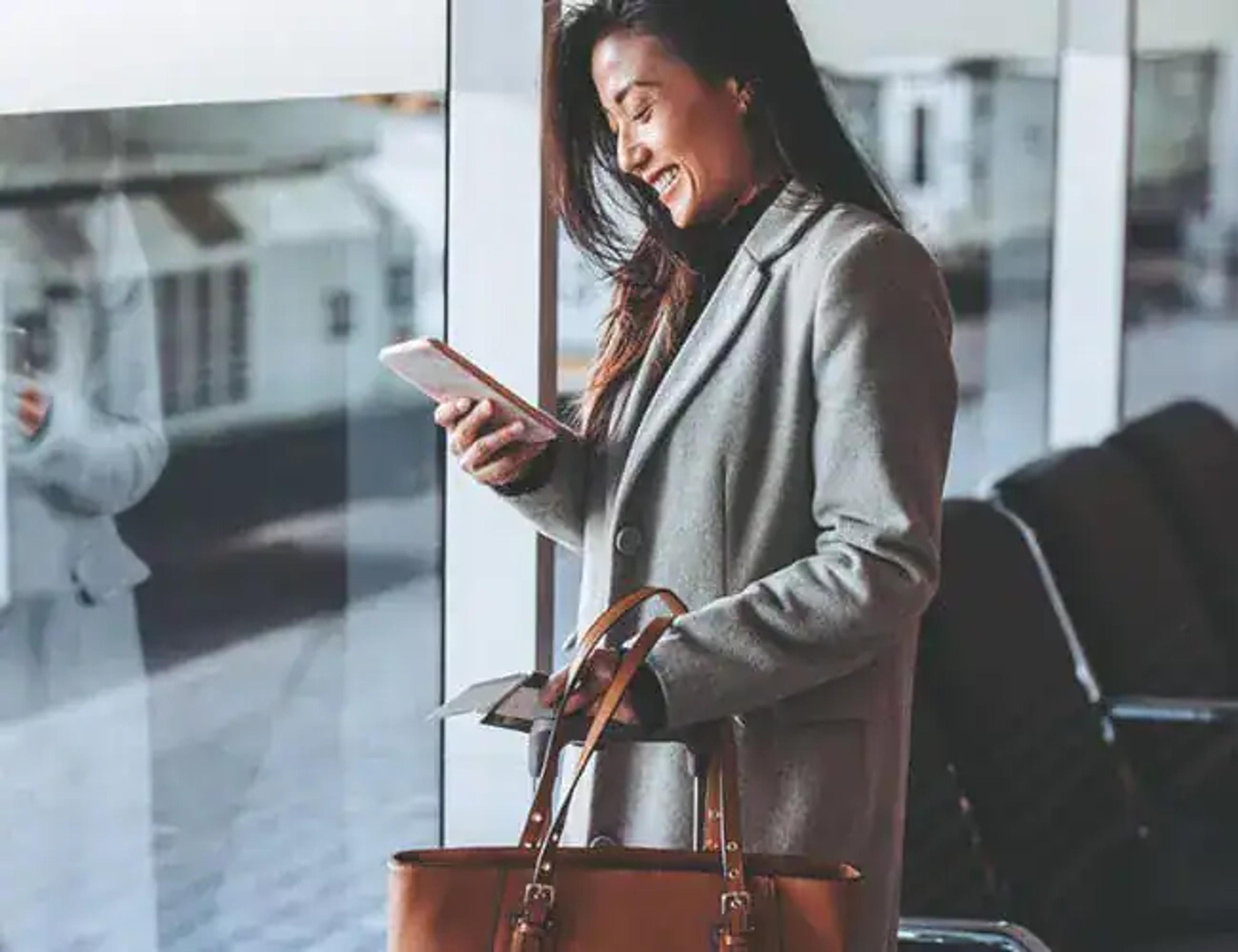 Femme d’affaires en voyage consultant son téléphone à l’aéroport