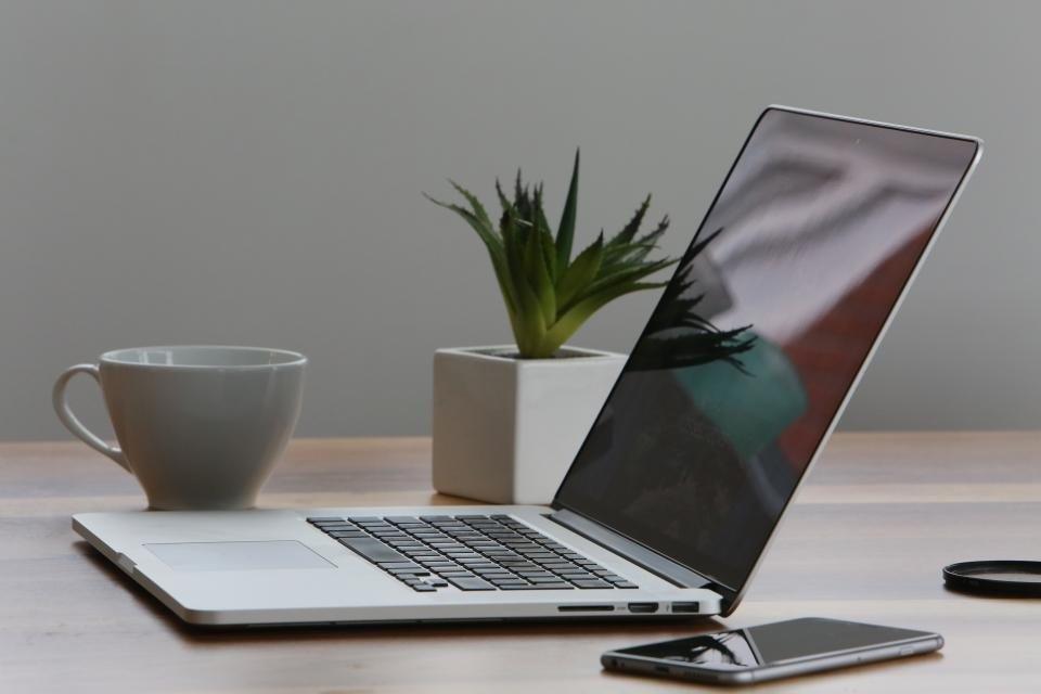 Escritorio ordenado con portátil, planta y taza de café para el mantenimiento de una web