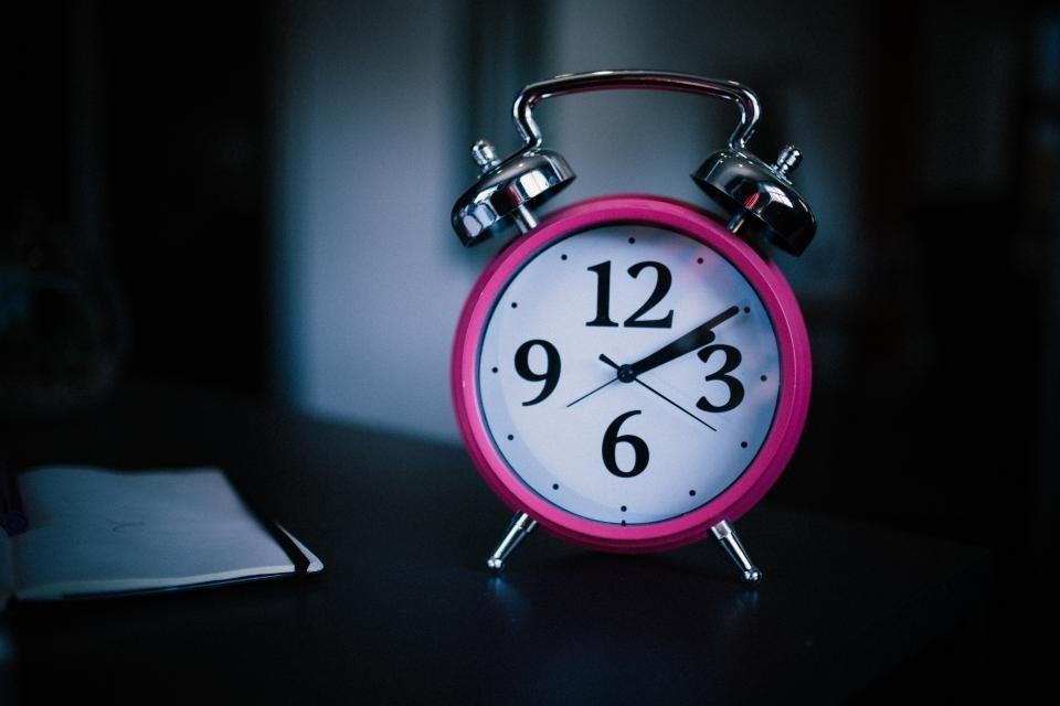 Reloj despertador rosado que recuerda la frecuencia de las actualizaciones de WordPress