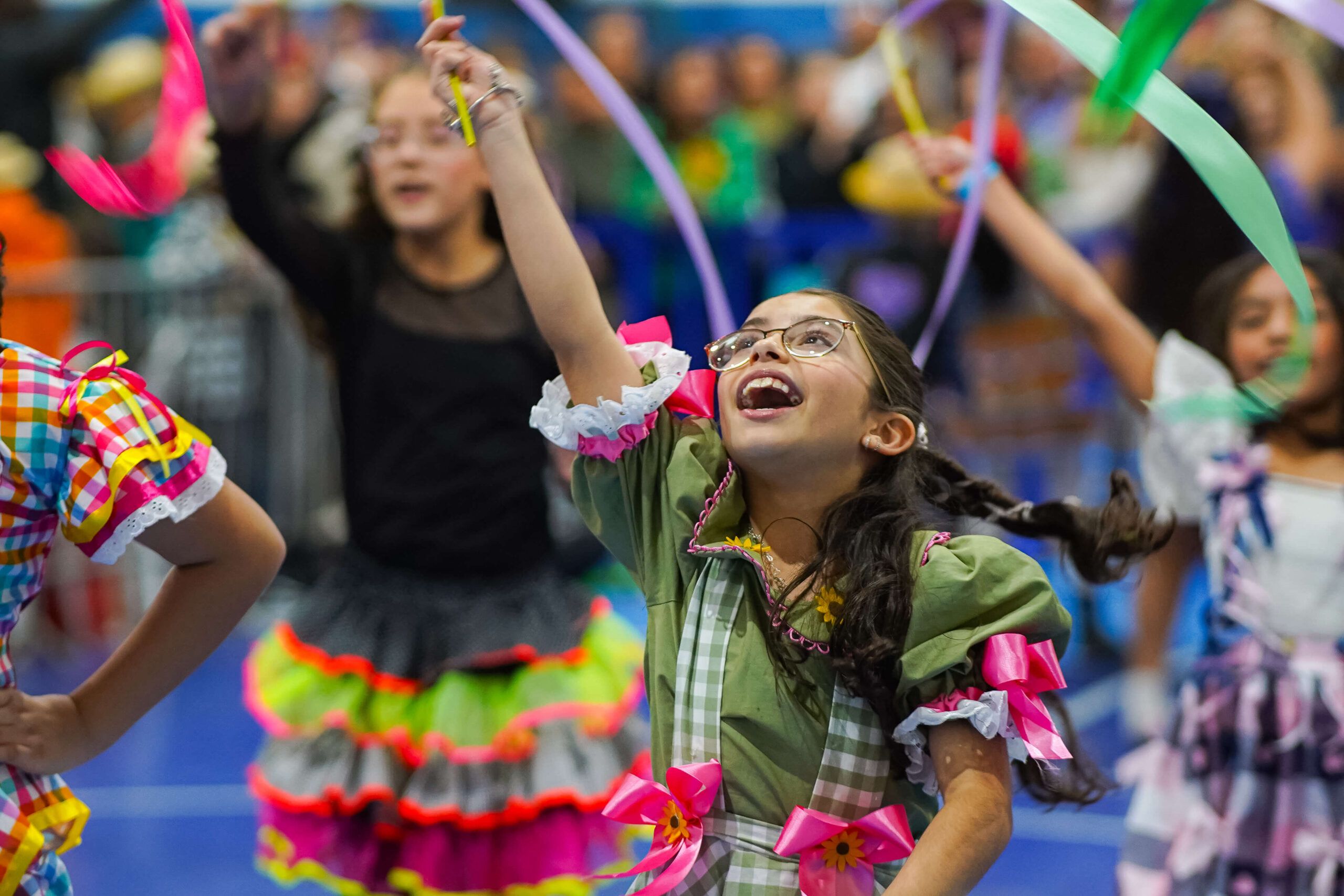 Estudante dança com fitas coloridas durante a Festa Julina do Stella Matutina