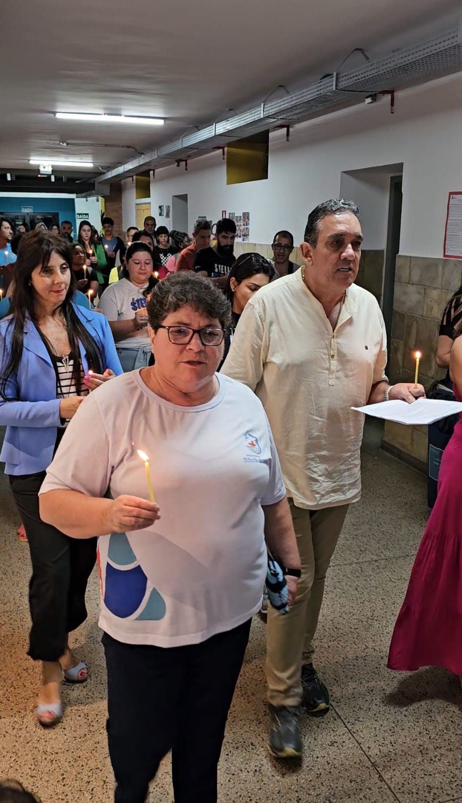Equipe pedagógica caminha com velas em procissão pelos corredores do Stella Matutina