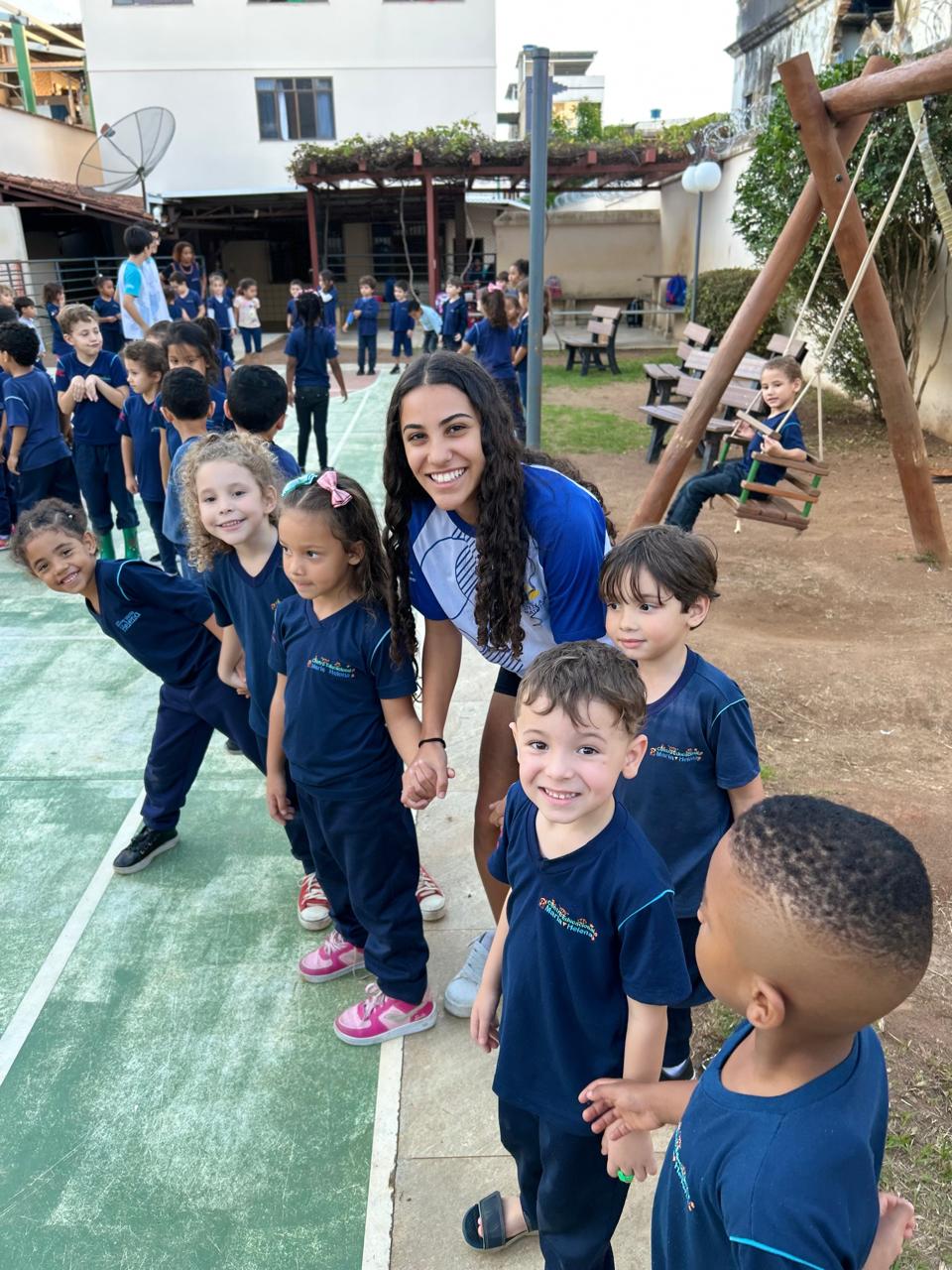 Jovem da Juventude Missionária acompanhada por crianças no pátio do Centro Educacional Maria Helena