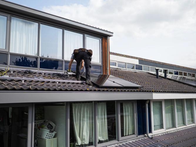 Monteur installeert zonnepanelen op een woningdak