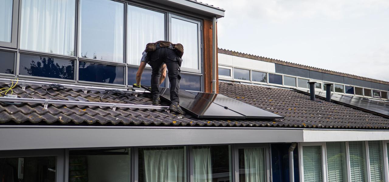 Monteur installeert zonnepanelen op een woningdak