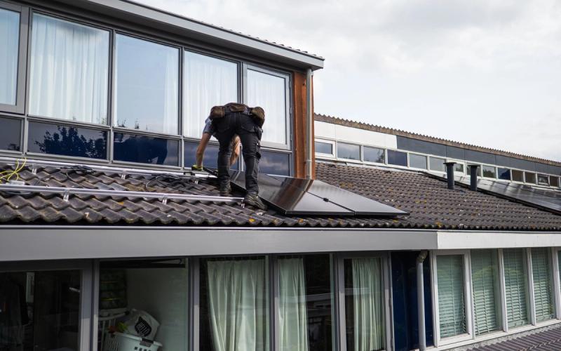 Monteur installeert zonnepanelen op een woningdak