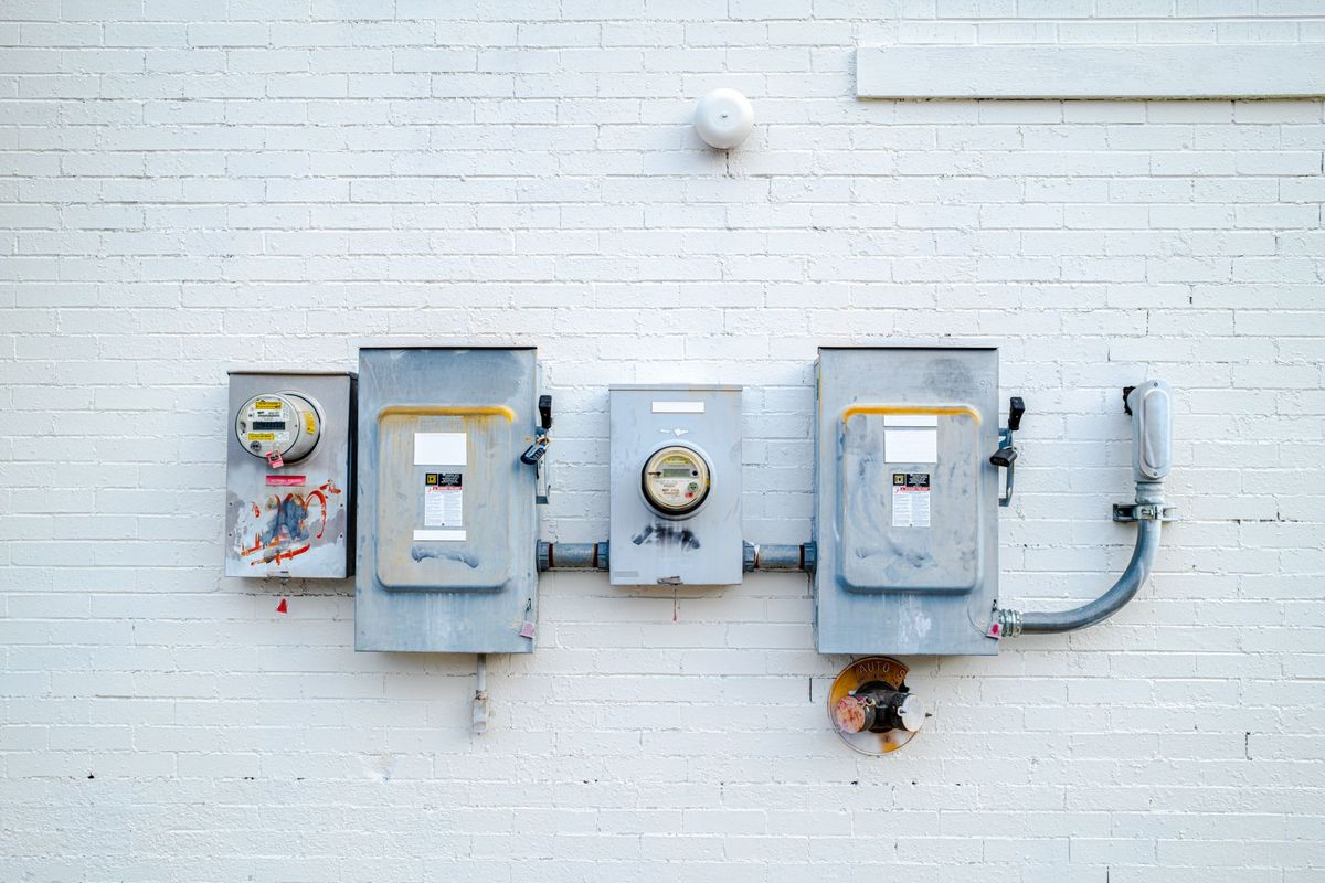 Meterkasten en elektriciteitsaansluitingen op een witte muur