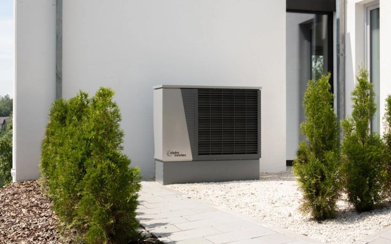 Warmtepomp buiten naast een moderne woning