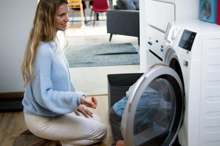 Moeder en kind zetten samen de wasmachine aan