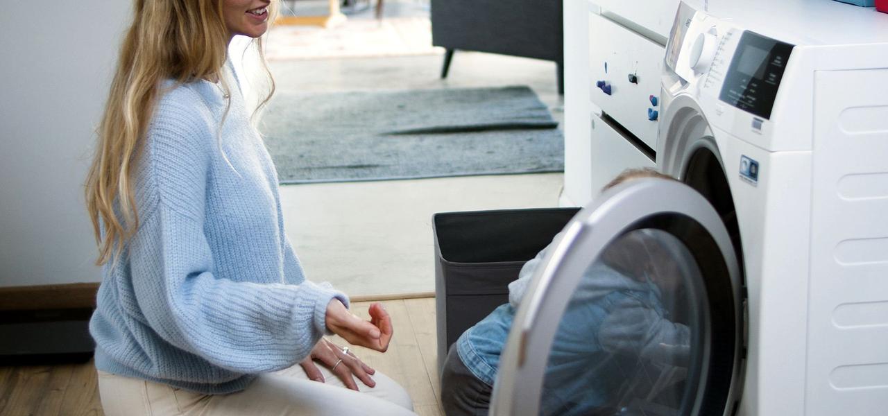 Moeder en kind zetten samen de wasmachine aan