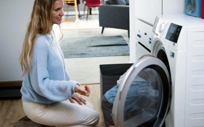 Moeder en kind zetten samen de wasmachine aan