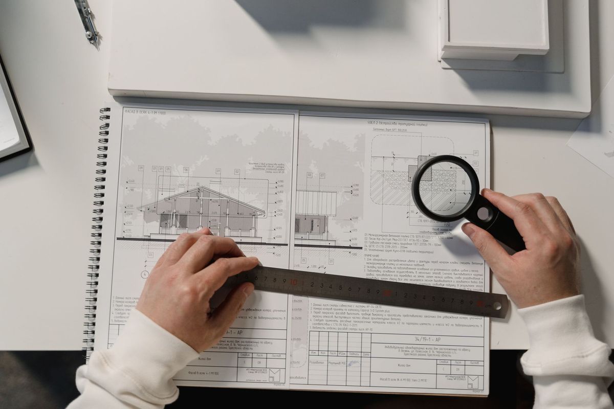 Hand met liniaal en vergrootglas boven een document