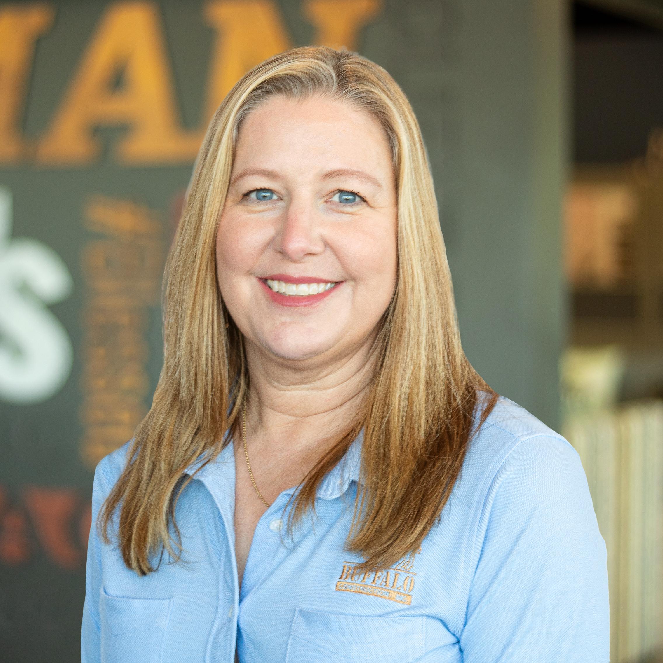 Dawn Starcher wearing a buffalo branded button down and standing in front of a company-branded wall.