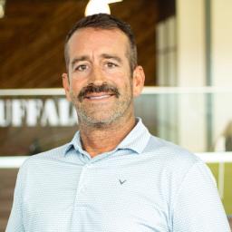 Donny Jenkins rocking a mustache, smiling and standing in buffalo's office space.