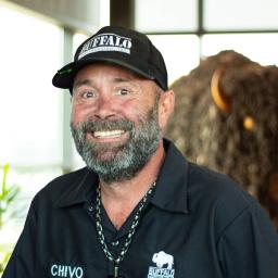 Anthony Abbott with a big smile as he stands in front of a statue of a buffalo.