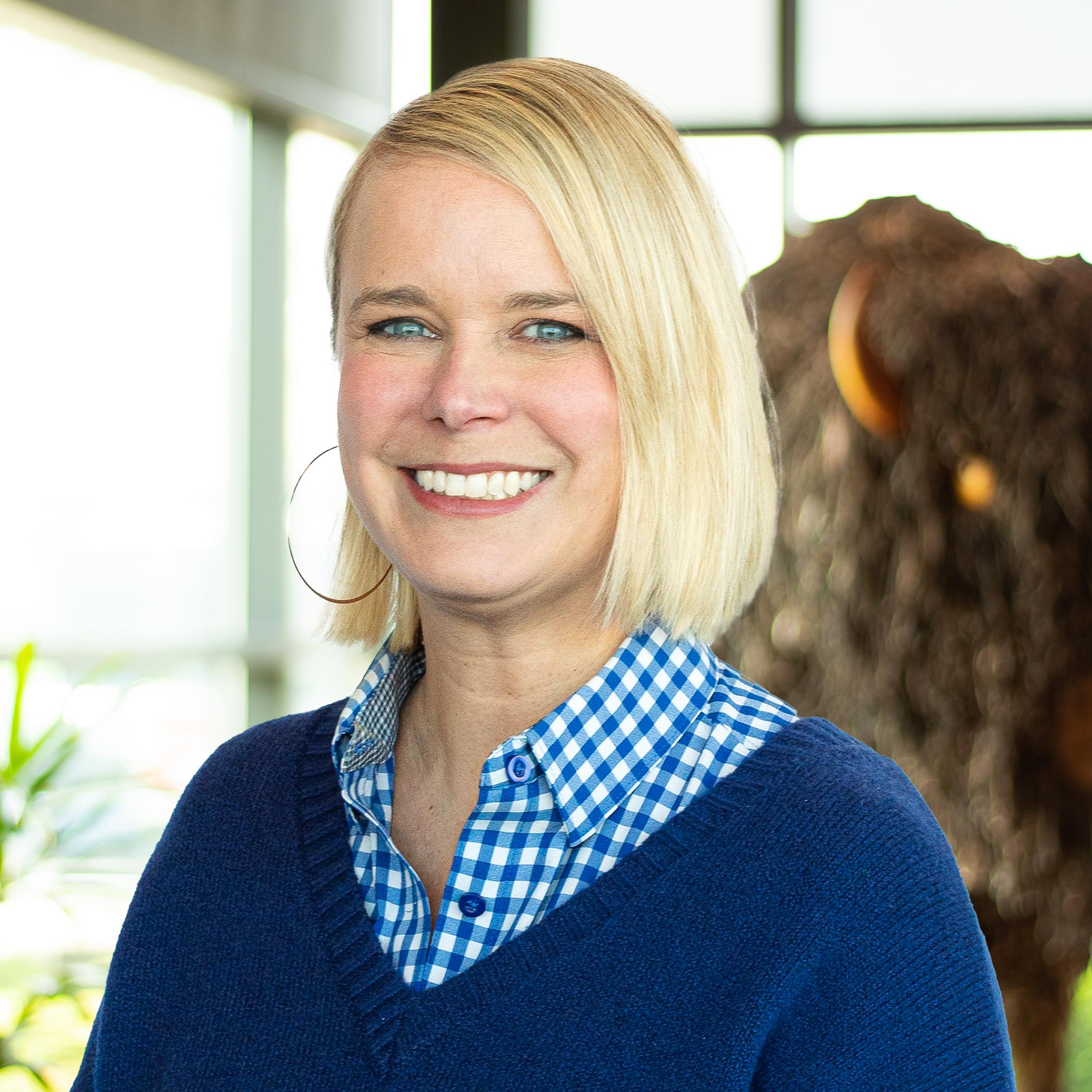Sierra Baumle smiling as she stands in front of a statue of a buffalo.