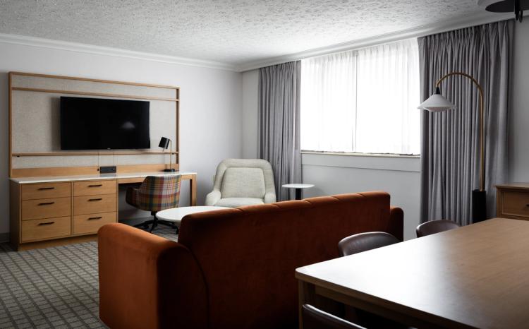 Open suite with TV, soft seating, and drapery