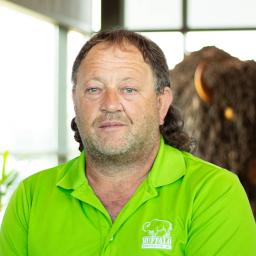 David Greenwell wearing a bright lime green buffalo branded polo as they stand in front of a statue of a buffalo.