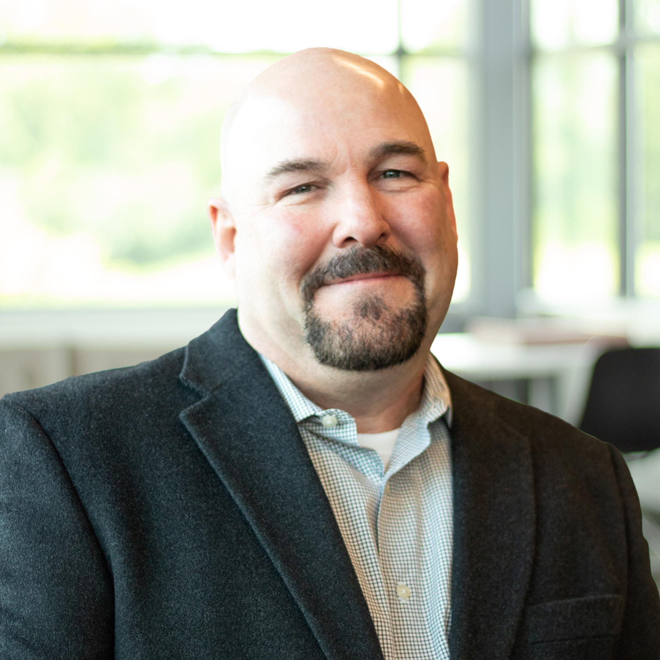 Thomas Prisock warmly smiling in a bright, modern office.