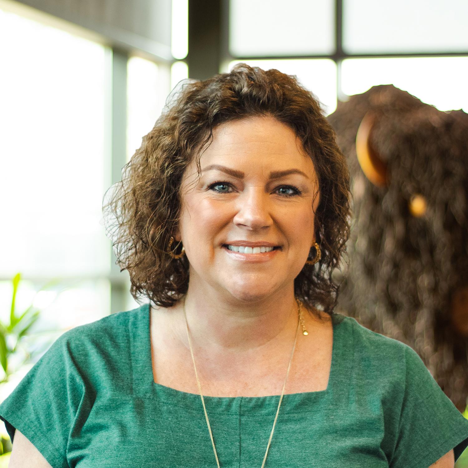 Valerie Eversole smiling as she stands in front of a statue of a buffalo.