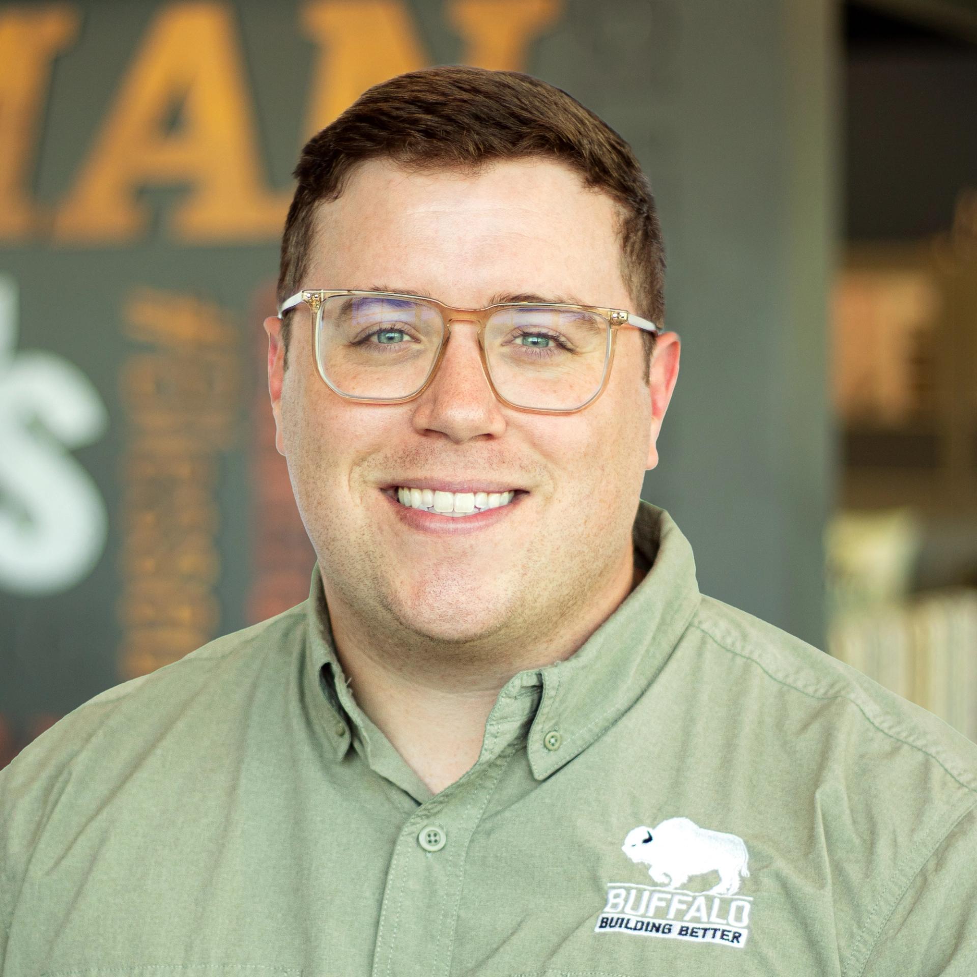 Jack Doherty wearing buffalo branded button down and standing in front of a company-branded wall.