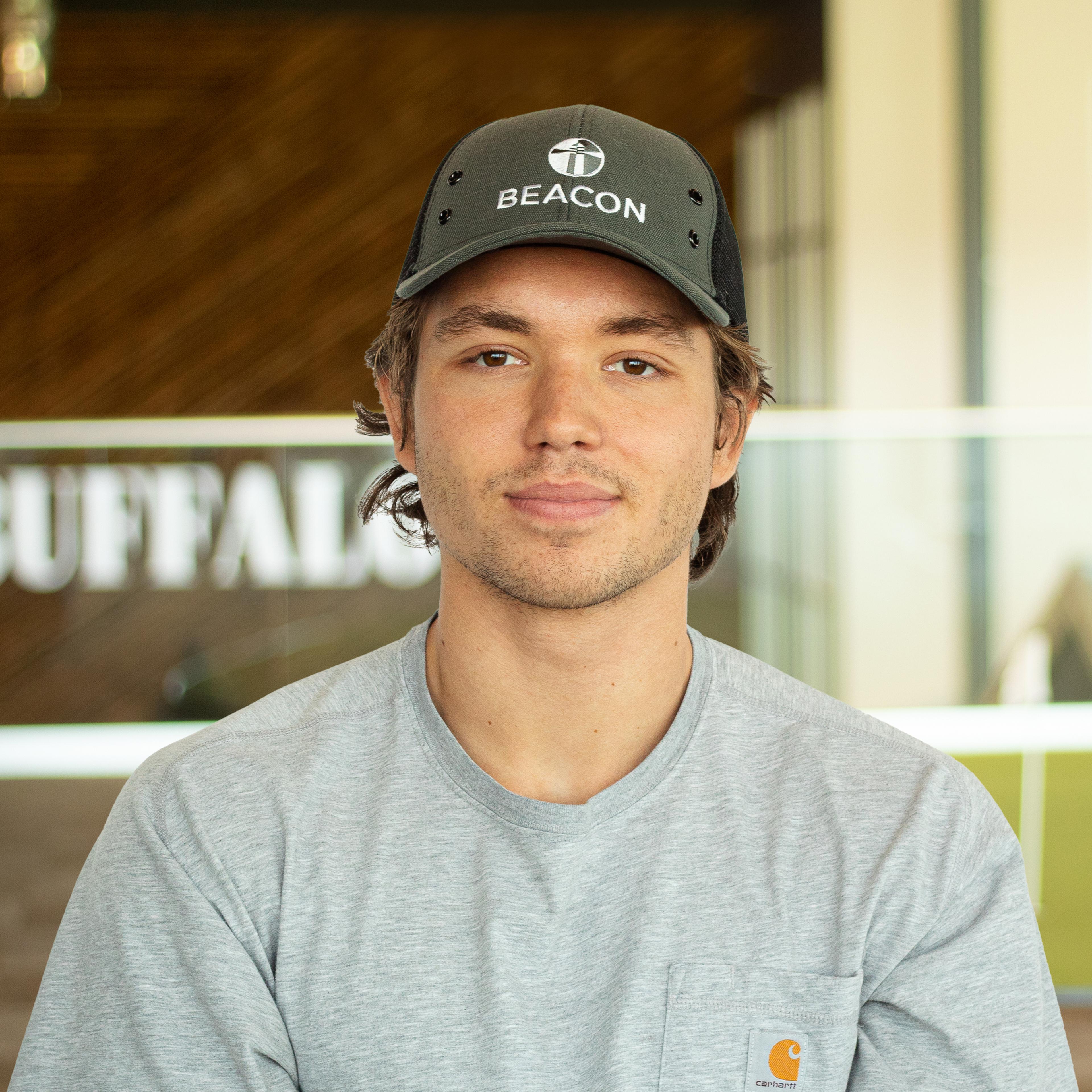 Ryan Coffman with a soft smile, wearing a gray Carrhartt shirt, standing in buffalo's office space.