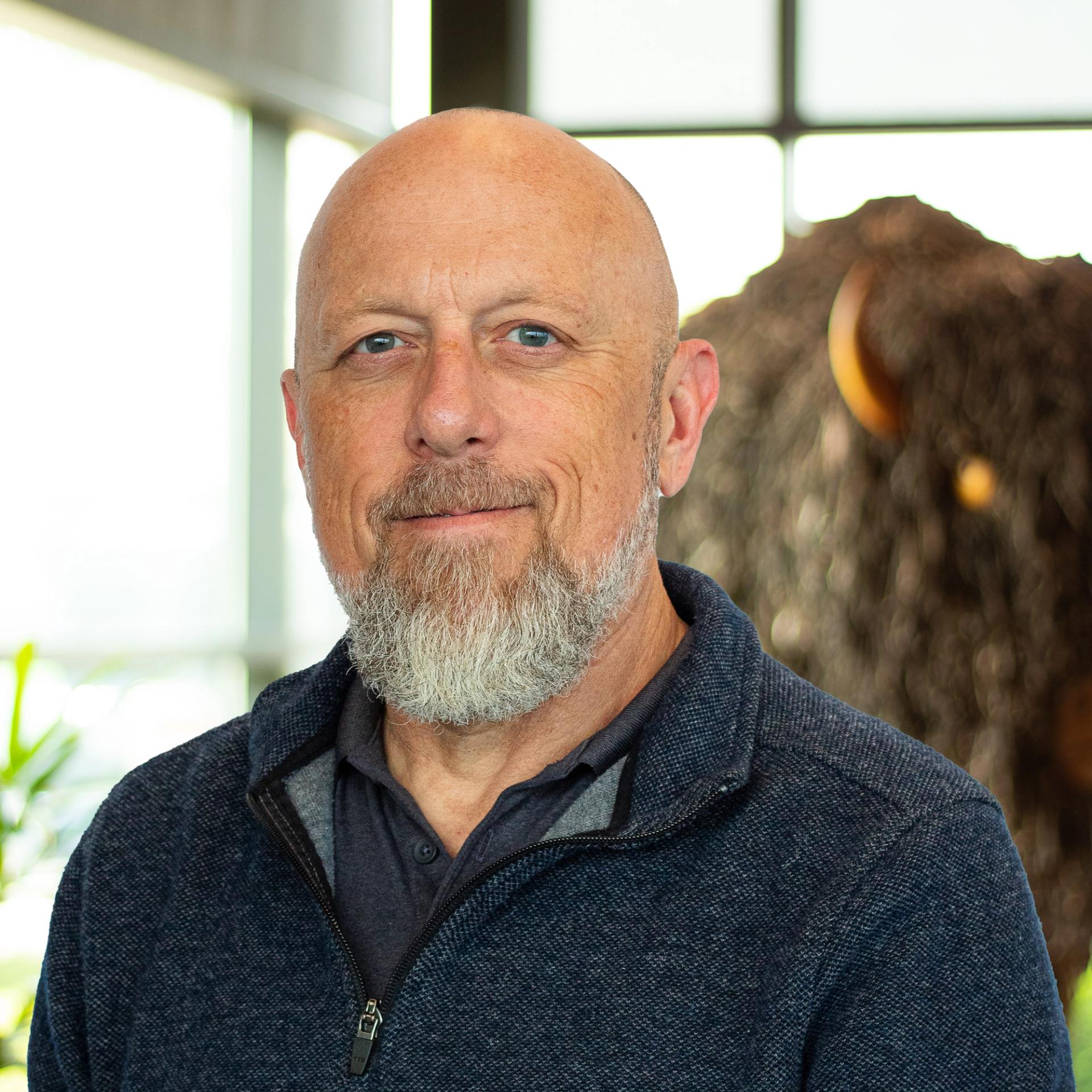 Larry Martin with a soft smile as he stands in front of a statue of a buffalo.