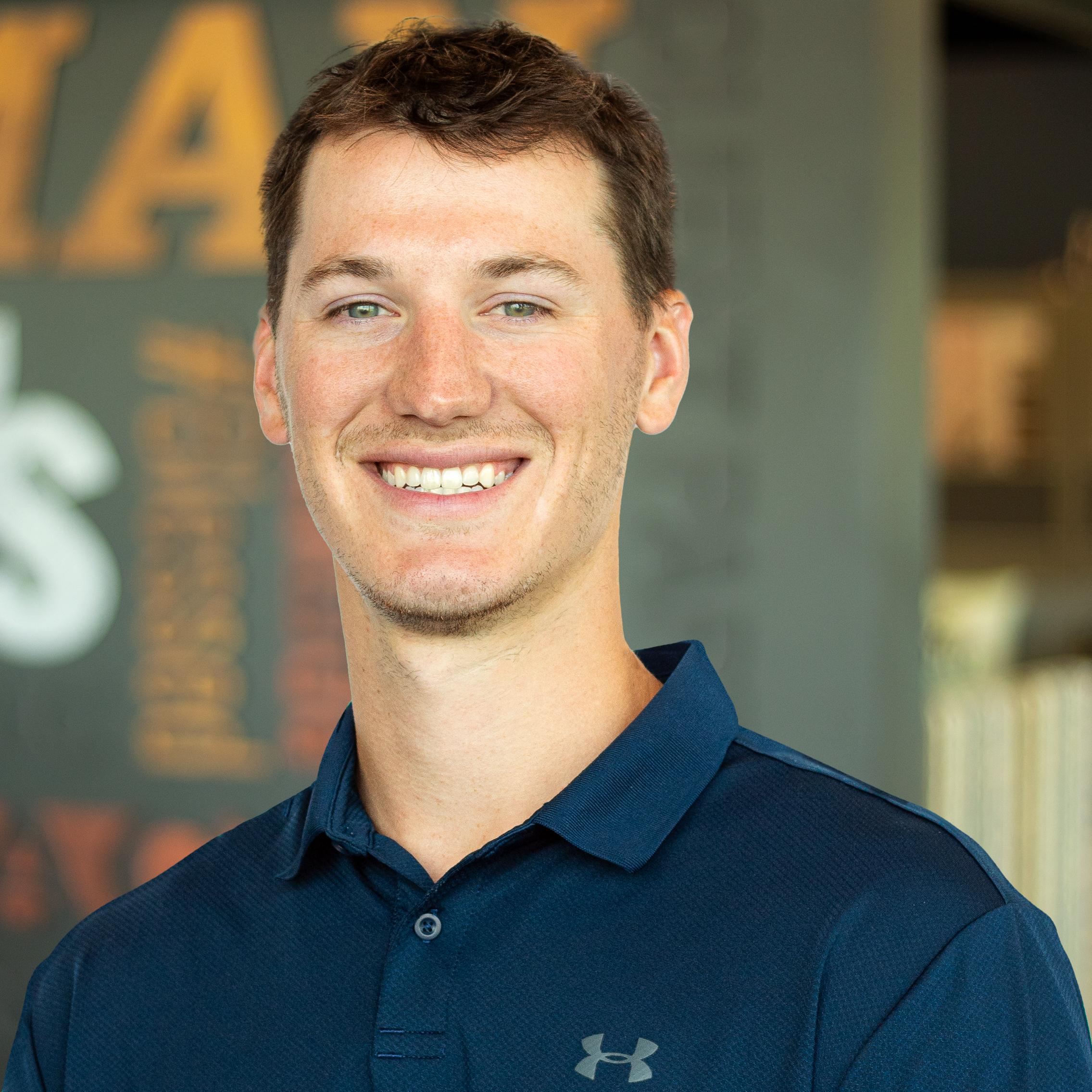 Lucas Meiners wearing a smile and standing in front of a company-branded wall.