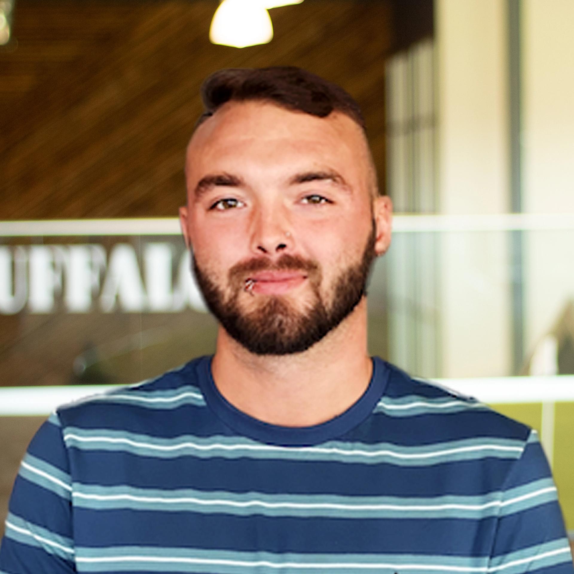 Caleb Marcum wearing a stripped shit and standing tall in buffalo's office space.