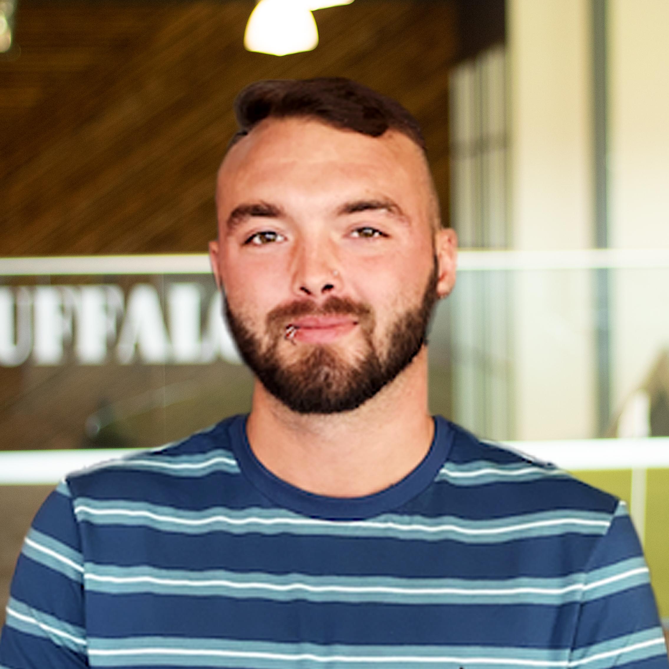 Caleb Marcum wearing a stripped shit and standing tall in buffalo's office space.