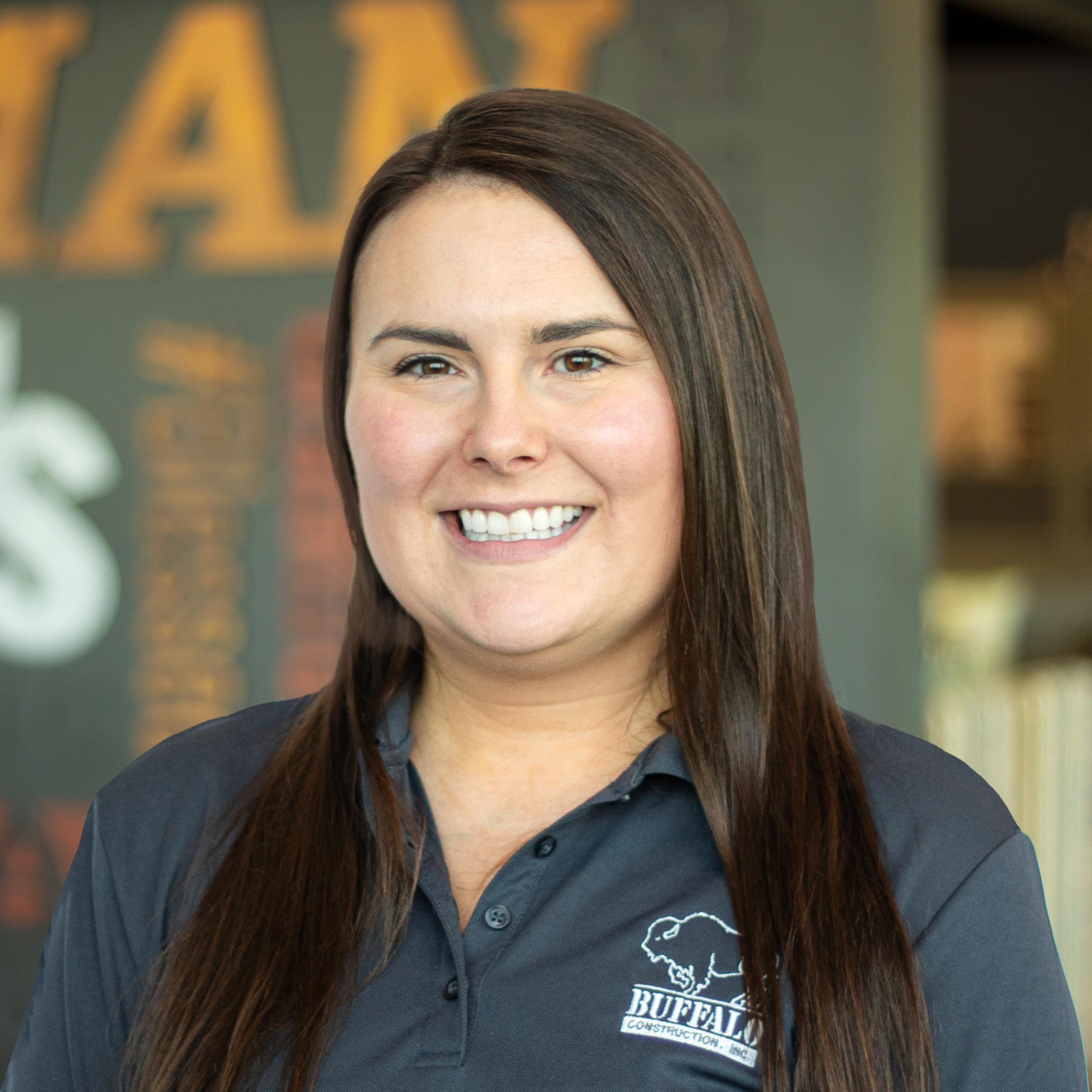 Natalie Harrison wearing a buffalo branded polo and standing in front of a company-branded wall.