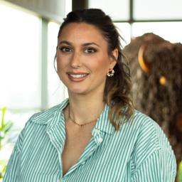 Taryn Day smiling as they stand in front of a statue of a buffalo.