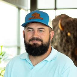 Chris Clark smiling as he stands in front of a statue of a buffalo.