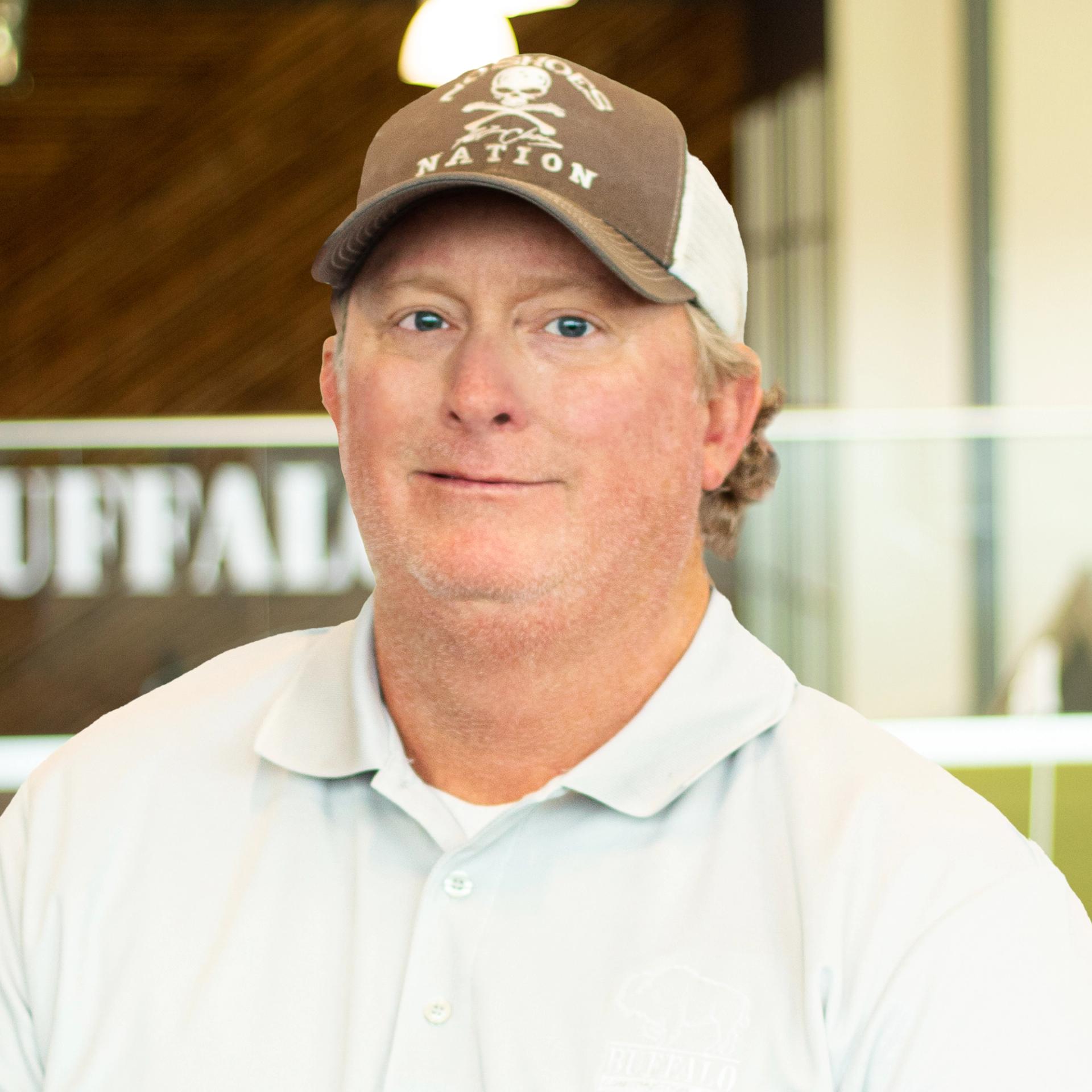 Chad Carson wearing a hat and polo, standing in buffalo's office space.