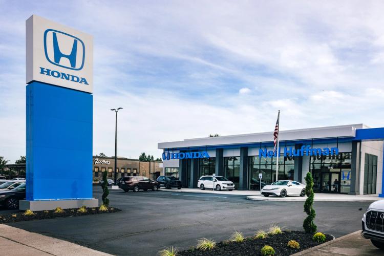 Completed exterior of Neil Huffman Honda featuring the dealership entrance, Honda monument sign, updated façade and landscaped parking area.