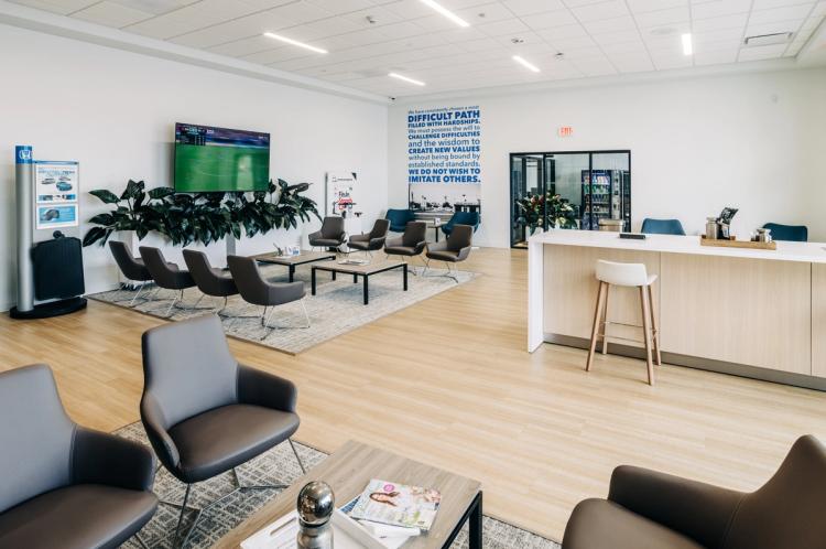Completed Neil Huffman Honda customer lounge featuring modern seating, light wood flooring, a hospitality counter and branded wall graphics.