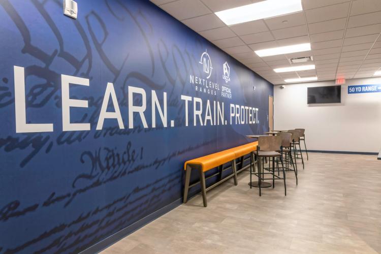 Branded “Learn. Train. Protect.” wall at Next Level Ranges.