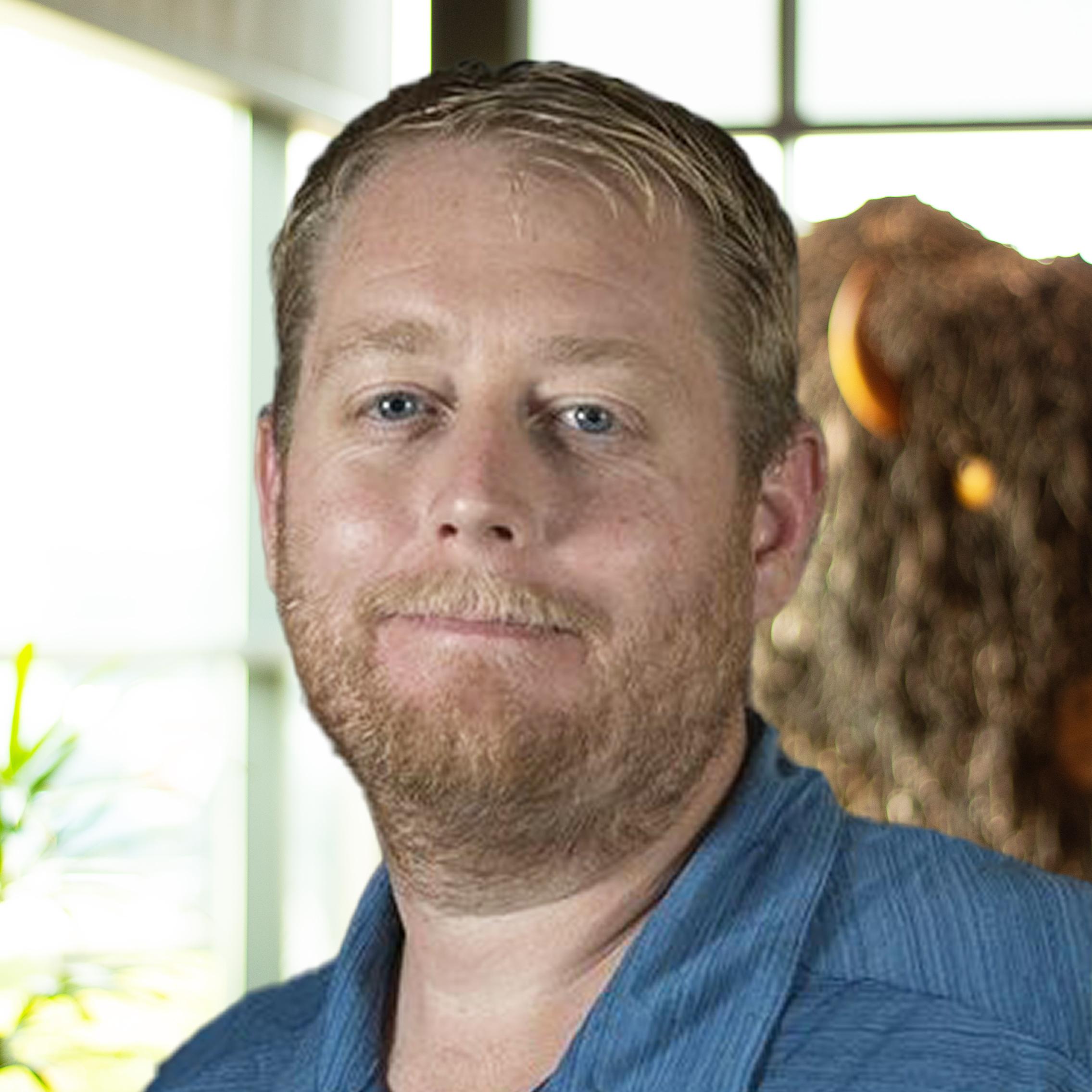 Jason Hunt smiling as they stand in front of a statue of a buffalo.