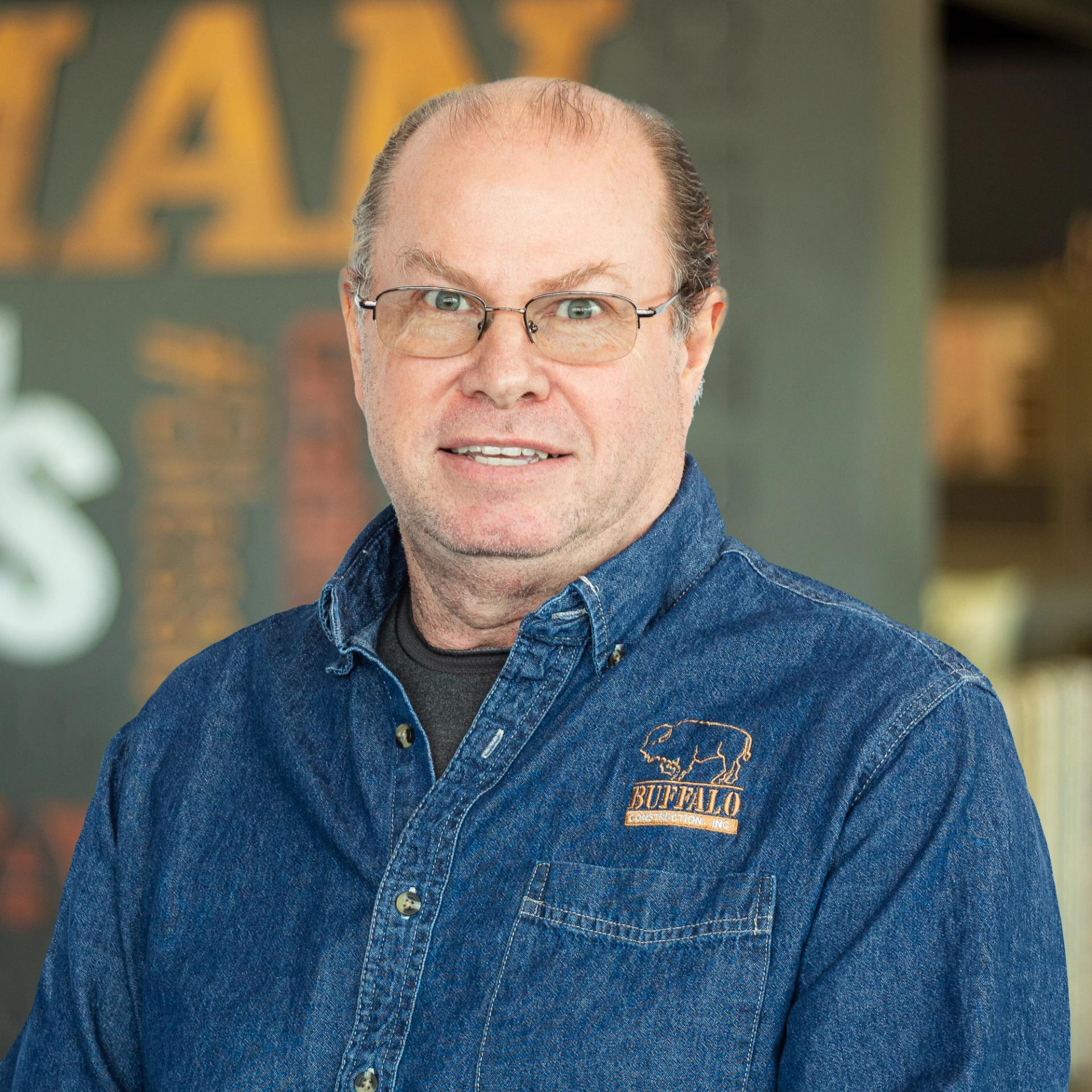 Philip "Krusty" Gamez wearing a buffalo branded button down and standing in front of a company-branded wall.