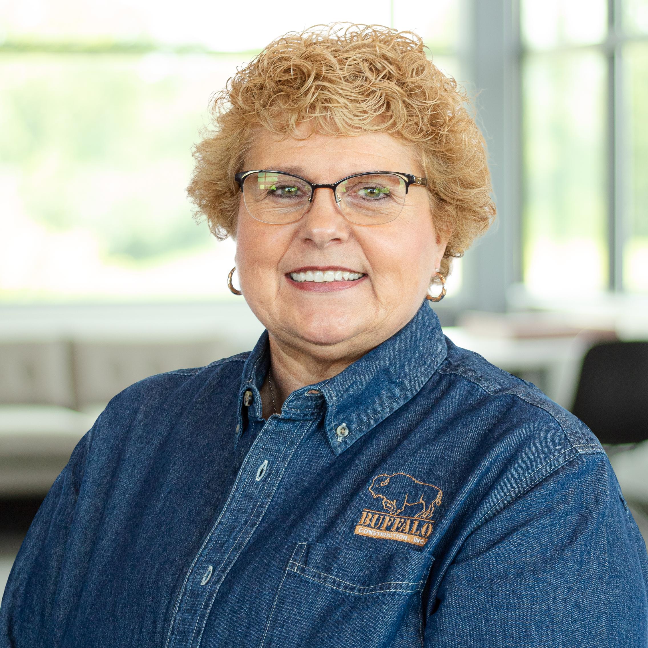 Sarah Sheilley wearing a smile and a buffalo branded button down, in a bright, modern office.