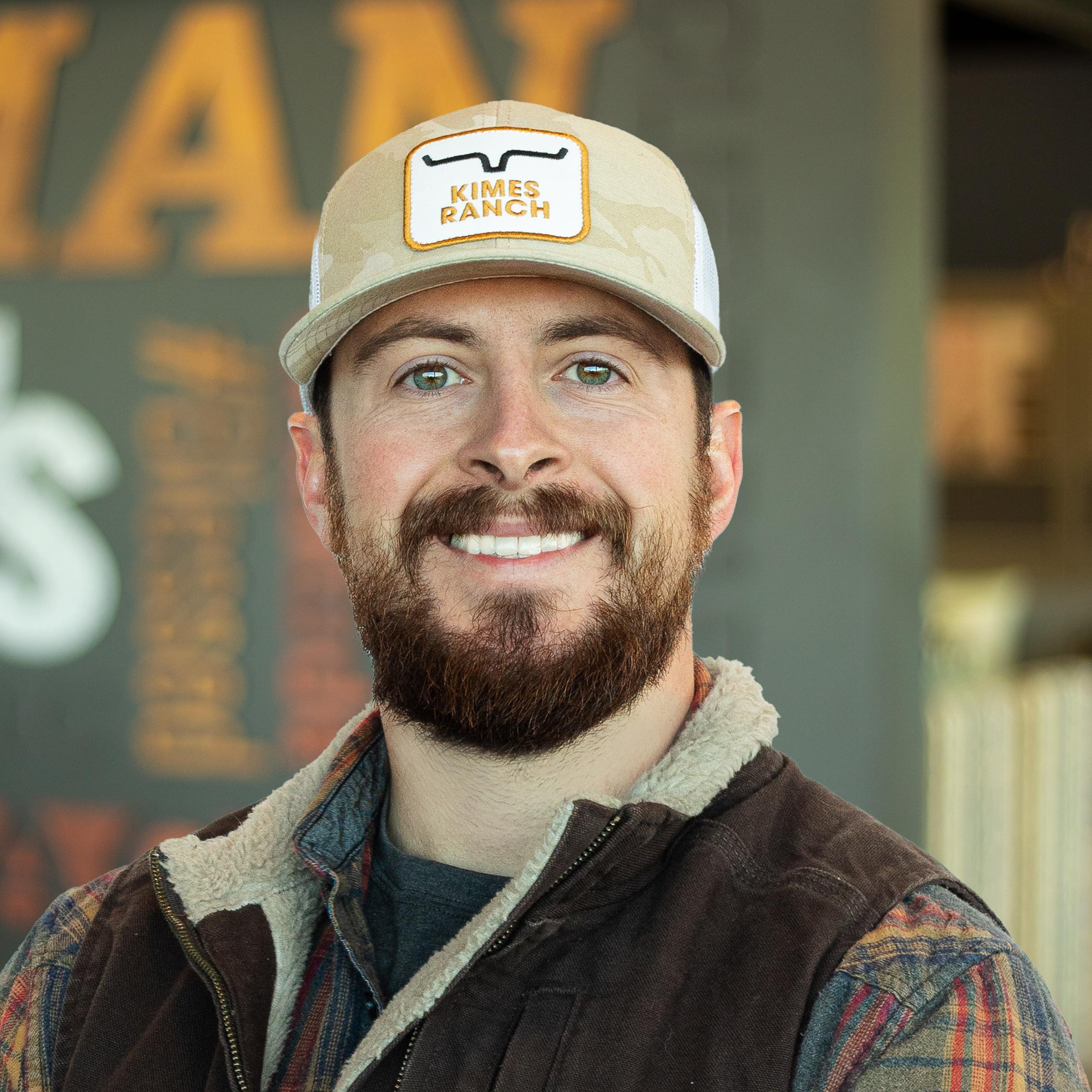 Garrett Young smiling and standing in front of a company-branded wall.